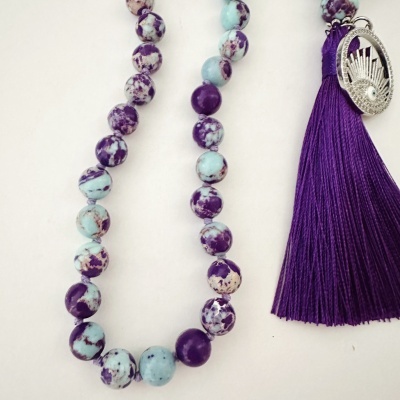 Colar de contas azul-claro e roxas com franjas roxas e pendente metálico