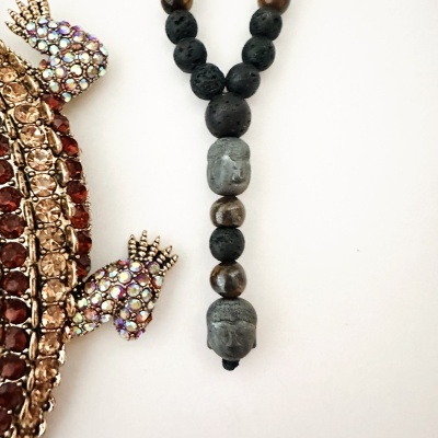 Colar com contas pretas e castanhas e broche dourado com pedras brilhantes