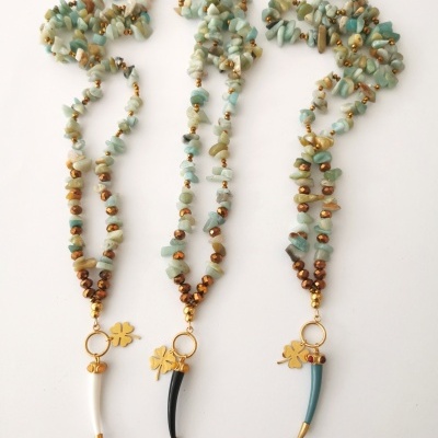 Três colares coloridos com pendentes de dente e flor dourada