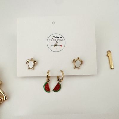 Conjunto de brincos dourados metálicos com tartaruga e melancia em cartão branco