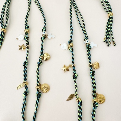 Pulseiras trançadas com pingentes dourados sobre fundo claro