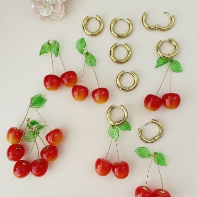 Brincos e argolas dourados com pendentes de cerejas vermelhas e verdes