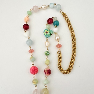 Colar colorido com contas diversas e corrente dourada sobre fundo branco