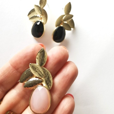 Brincos e anel dourados com pedras pretas e rosadas em forma oval e detalhes de folhas