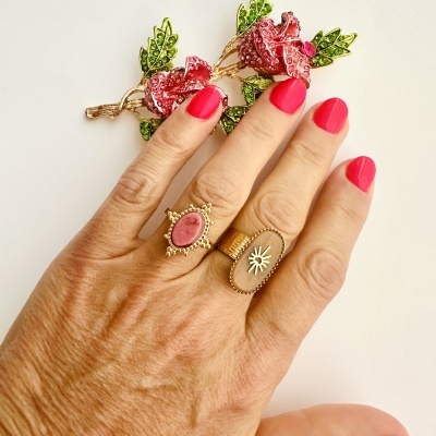 Mão com dois anéis dourados e unhas pintadas de rosa