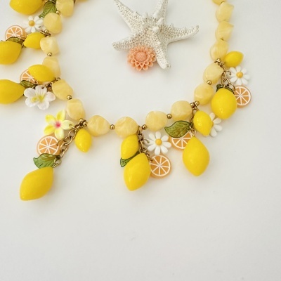 Colar decorativo com limões, flores e folhas sobre fundo branco