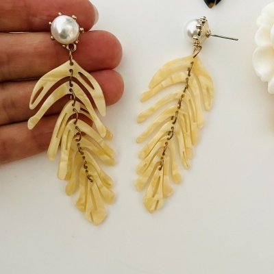 Brincos pendentes bege com base redonda pérola e estrutura em metal dourado