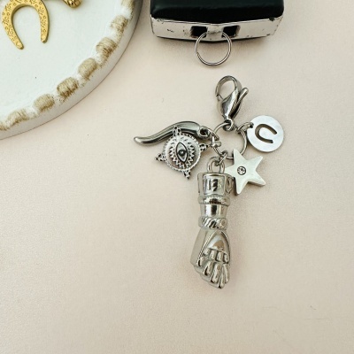 Chaveiro metálico prateado com vários pendentes ao lado de prato branco e ferradura dourada