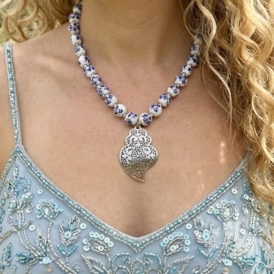 Colar com contas brancas e azuis e pendente metálico trabalhado