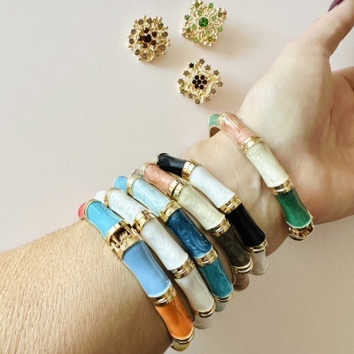 Pulseiras rígidas coloridas com detalhes dourados e padrões marmoreados no pulso