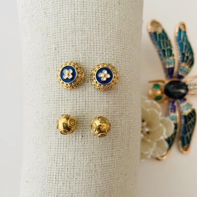 Dois pares de brincos dourados e broche de libélula colorido sobre tecido claro