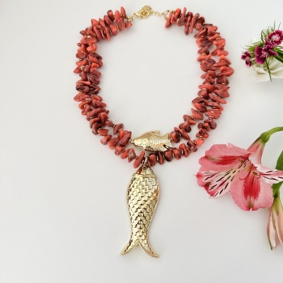 Colar vermelho com pendentes dourados em forma de peixe junto a flores