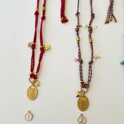 Colares artesanais com medalhas ovais douradas e fios entrelaçados vermelhos e azul-claros