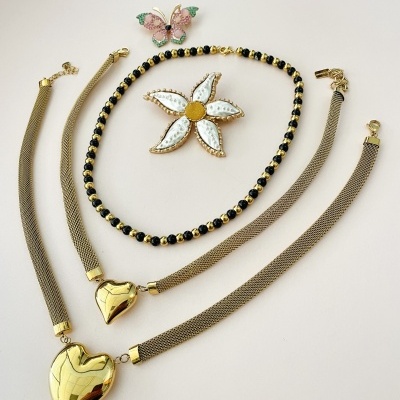Conjunto de joias com colares dourados, broche de flor e anel ou broche de borboleta colorida