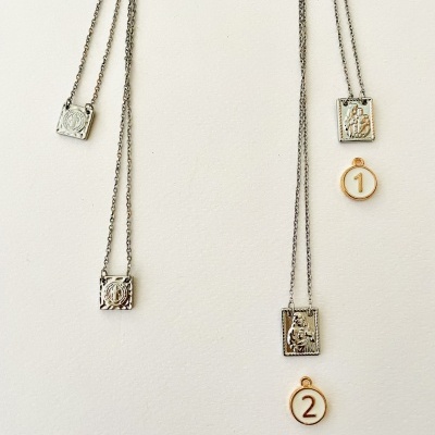 Vários colares com pendentes metálicos e medalhões numerados sobre fundo branco