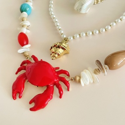 Colares com pendentes de caranguejo vermelho e concha dourada, contas coloridas e pérolas artificiais