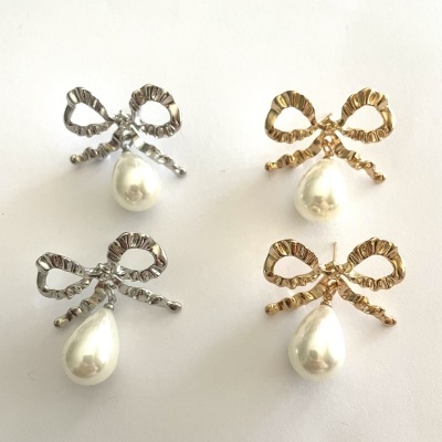 Quatro brincos com laços dourados e prateados e pérolas penduradas