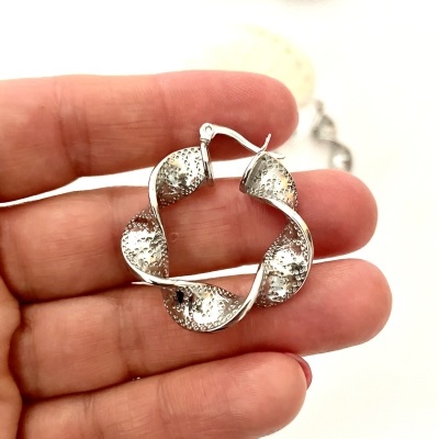 Brinco de argola prateado texturizado entrelaçado na mão