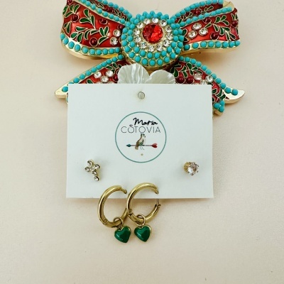 Conjunto de três pares de brincos fixados em cartão branco com o logo Maria Cotovia, com laço colorido em fundo