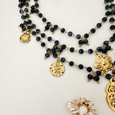 Colares com contas pretas e pendentes dourados de concha, flor, medalha e inseto