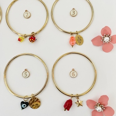 Pulseiras douradas numeradas com pendentes coloridos e flores decorativas cor-de-rosa