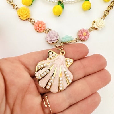 Colar com pendente de concha com pérolas e flores coloridas na corrente.