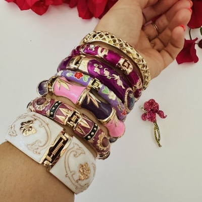 Pulseiras coloridas em pulso feminino com fundo branco e flores vermelhas