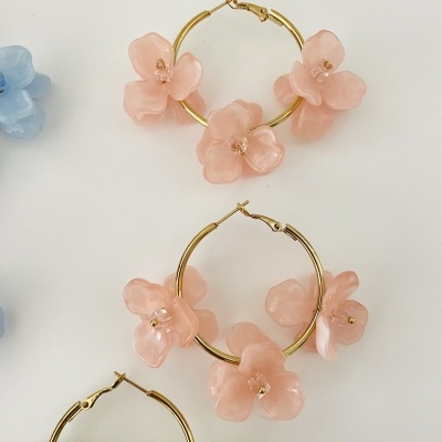 Brincos argola com flores cor-de-rosa e verdes sobre fundo branco