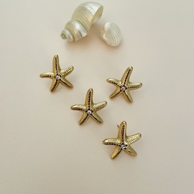 Brincos estrela-do-mar dourados com pedra brilhante e conchas pequenas em fundo branco