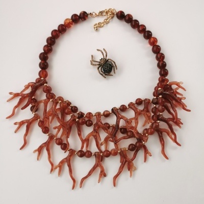 Colar com contas castanhas e pendentes cor de coral e uma pequena aranha decorativa