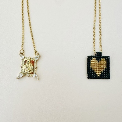 Dois colares com pendentes dourados e pretos, pendurados lado a lado