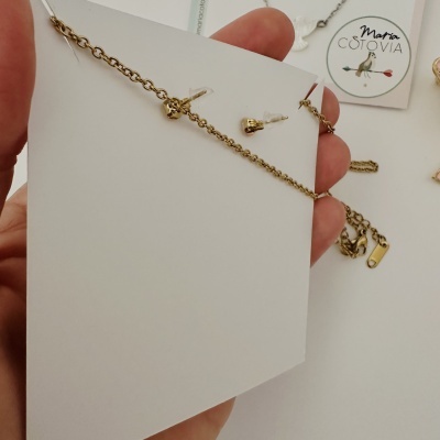 Conjunto de brincos e pulseira dourados e cartão com logotipo Maria Cotovia