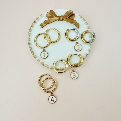 Quatro pares de brincos de argola em dourado e prata numa placa branca decorativa