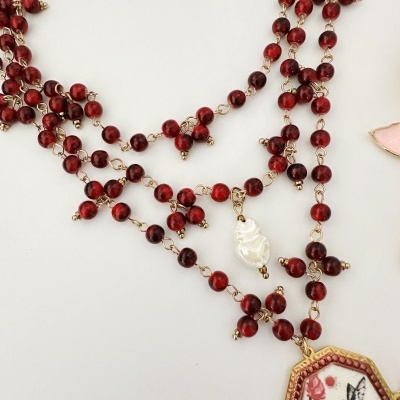 Colar com contas vermelhas, corrente dourada, pendente com pintura de pássaro e flores, e pérola branca irregular.