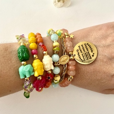 Pulseiras coloridas com figuras de Buda e medalha dourada numa mão