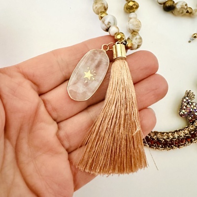 Colar com conta de pedra e franja rose gold na mão