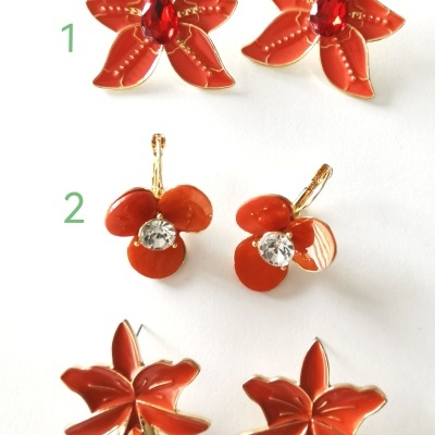 Três pares de brincos florais vermelhos com pedras coloridas e detalhes dourados sobre fundo branco