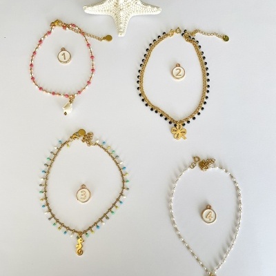 Quatro pulseiras coloridas com medalhas numeradas de 1 a 4 sobre fundo branco e estrela-do-mar decorativa