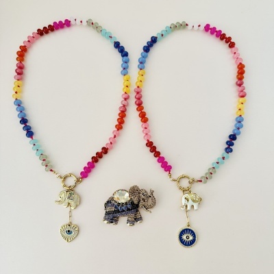 Bijuterias coloridas com pendentes de elefante e símbolos sobre fundo branco.