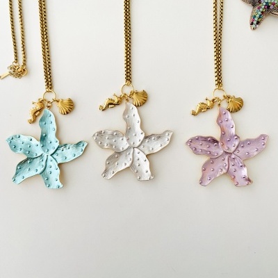 Três colares com pingentes de estrela-do-mar coloridas e pequenos detalhes dourados