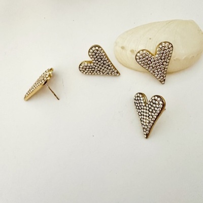 Brincos dourados em forma de coração com pedras brilhantes sobre fundo branco