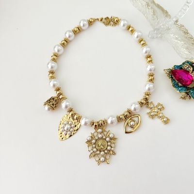 Colar com pérolas, contas douradas e pendentes variados sobre fundo branco