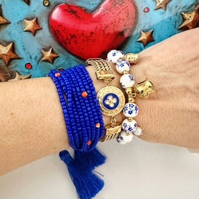 Três pulseiras coloridas femininas no pulso com fundo decorativo de coração e estrelas
