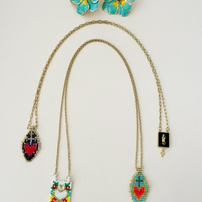 Colares dourados com pendentes de contas coloridas e brincos florais azuis com amarelo
