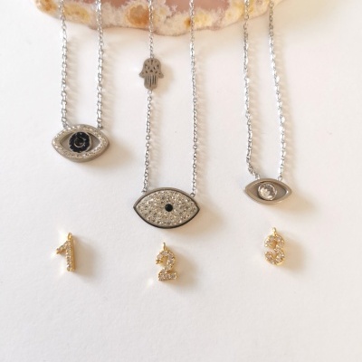 Colares prateados com pendentes de olhos e brincos dourados numerados