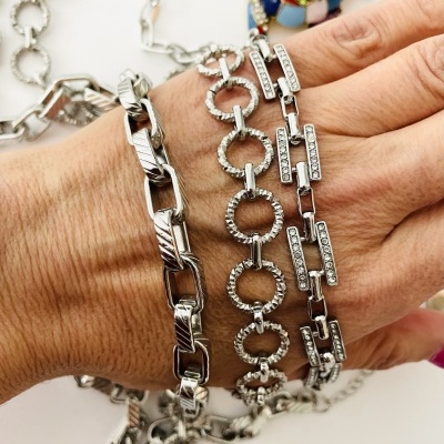 Três pulseiras prateadas com diferentes designs num pulso