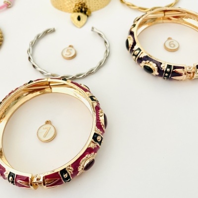 várias pulseiras e braceletes metálicos com etiquetas numeradas em fundo branco