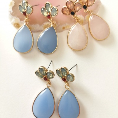 Três pares de brincos gota pendente com pedras coloridas e moldura dourada