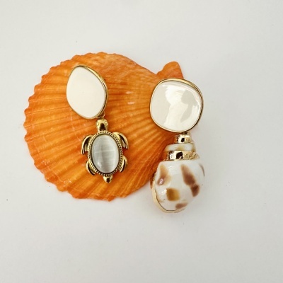 Brincos em metal dourado com pedras brancas e pendentes de tartaruga e concha