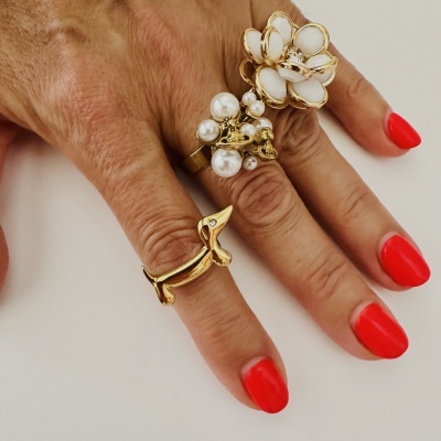 Mão com três anéis dourados distintos e unhas vermelhas